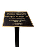 Plaque on a stand with engraved text recognizing Linda and Jerry Soltys for their community dedication.