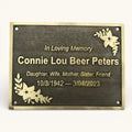 Memorial plaque with engraved text and floral designs on a white background