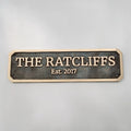 Brass house nameplate with 'THE RATCLIFFS Est. 2017' text on a gray background