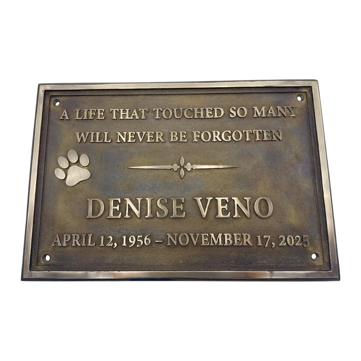 Bronze plaque with engraved text and paw print on a white background