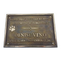 Bronze plaque with engraved text and paw print on a white background